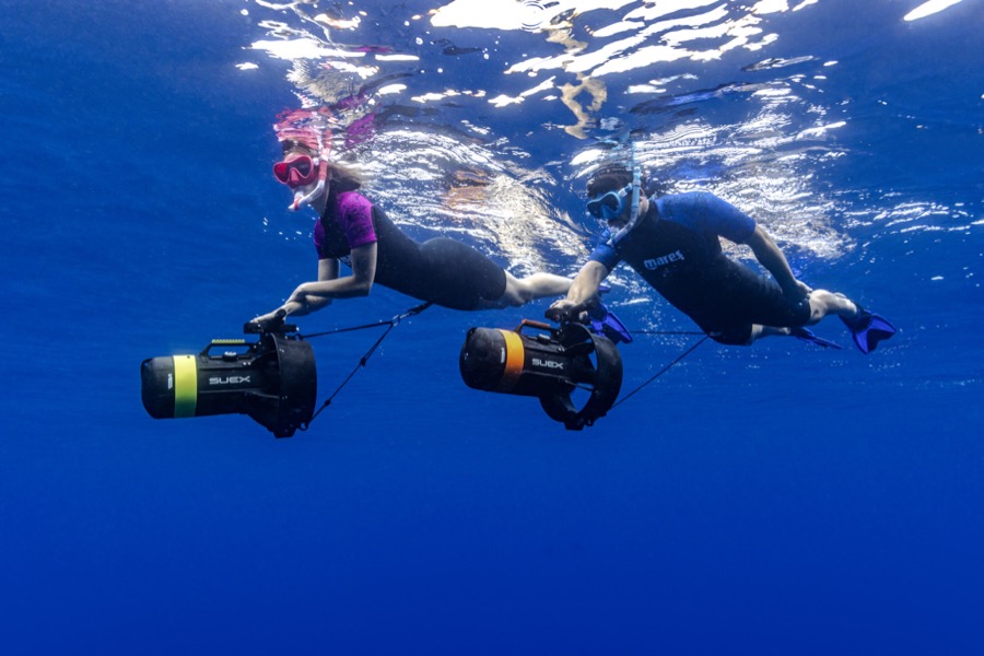 Couple gliding side by side with DPV scooters